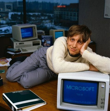 Bill Gates sitting with a computer running Microsoft software.